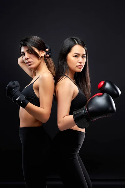 portrait of confident athlete women standing side by side wearing boxing gloves