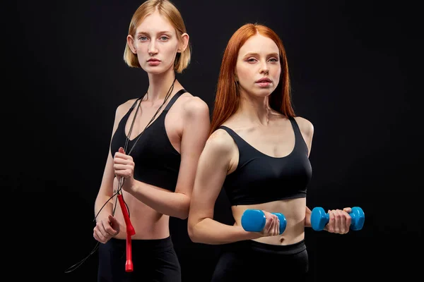 Two sportive caucasian women go in for sport, using dumbbells and skipping rope — 스톡 사진