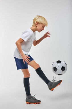 Stüdyoda futbol topuyla profesyonel olarak antrenman yapan beyaz çocuk.