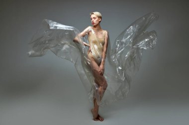 Stüdyoda şeffaf plastik torbayla poz veren ince kadın model.