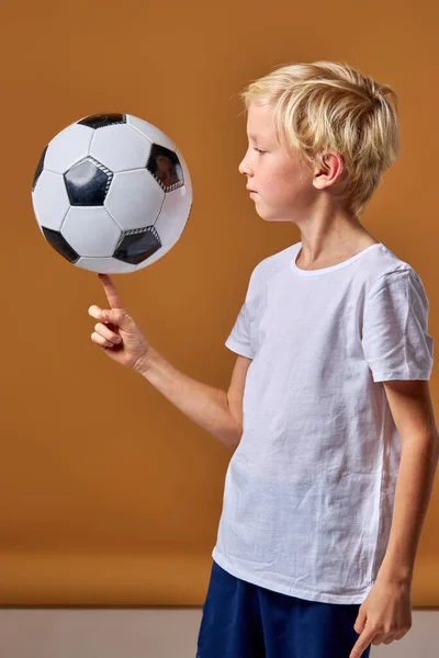 Спортивний футболіст хлопчик обертає м'яч на пальці — стокове фото