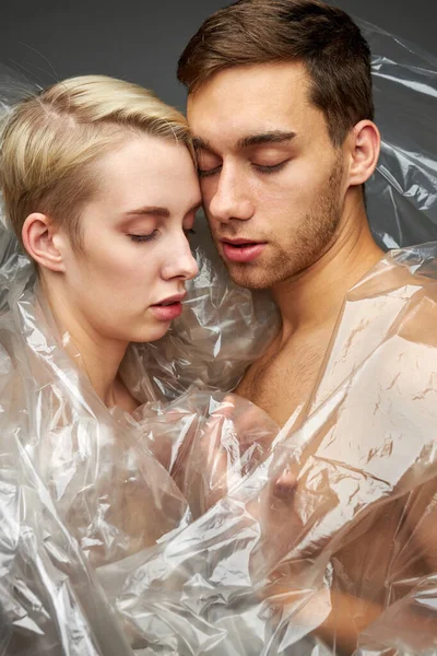 Weak exhausted couple in plastic transparent bag, suffering from garbage everywhere — Stock Photo, Image