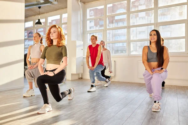 group of youth stretching legs before dance class