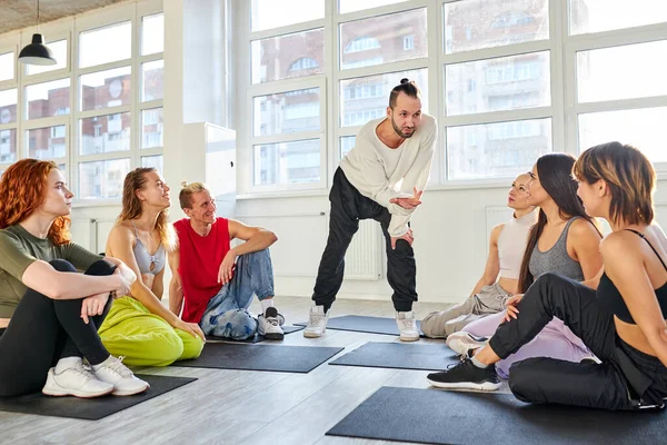 Zelfverzekerde mannelijke choreograaf legt de noodzaak van training en lichaamsbeweging voor het dansen uit — Stockfoto