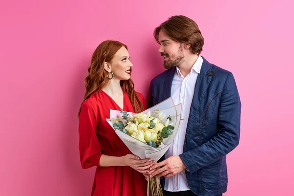 Ρομαντική ημερομηνία: καυκάσιος τύπος παρουσιάζει λουλούδια σε νεαρή κοκκινομάλλα κυρία — Φωτογραφία Αρχείου