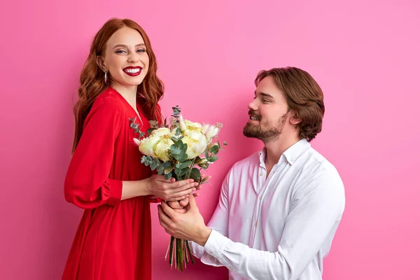 Joyeux jeune couple dans les vêtements de fête debout isolé sur fond rose, célébrer — Photo