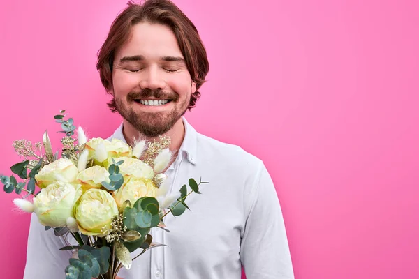 Man met een boeket bloemen te wachten op een datum verblijven op roze achtergrond — Stockfoto