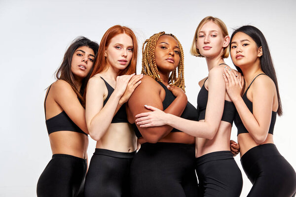 Четыре тощих модели и одна толстая африканская женщина, изолированная на белом