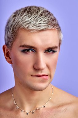 Makyajlı kadın gömleksiz bir adam kameraya poz veriyor.