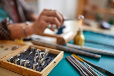 Erkek kuyumcu bir yüzüğü lehimlemek için alev feneri kullanıyor.