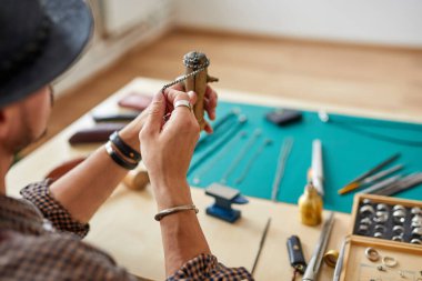 Mükemmelliğe giden yolda. Erkek kuyumcu elleri kuyumcu dükkanında gümüş zincir parlatıyor.