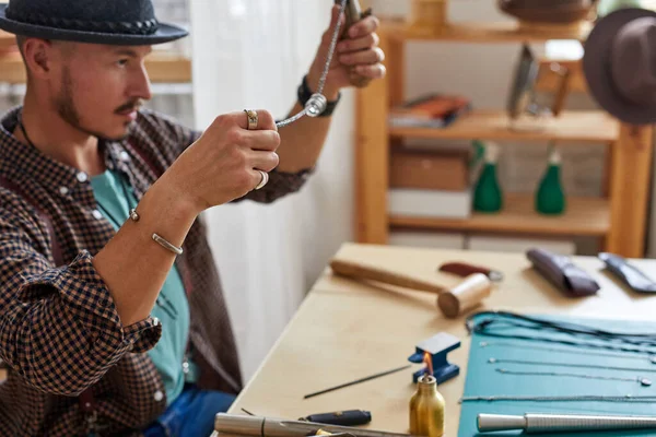 Ювелир ремонтирует ювелирные изделия, держит кольца на цепи — стоковое фото