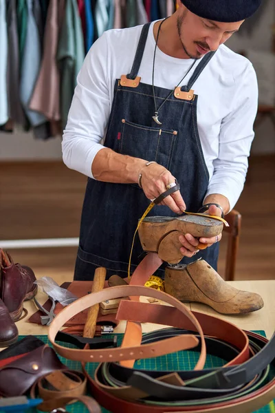 Мастер-сапожник шьет обувь в мастерской — стоковое фото