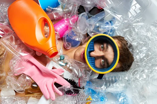 Uomo che annega sotto i recipienti di plastica mucchio, immondizia, spazzatura — Foto Stock