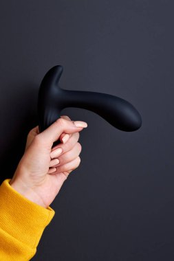 Elinde siyah vibratör tutan bir kadının kesilmiş fotoğrafı.