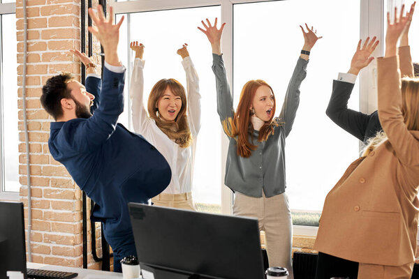 happy optimistic team of business people raising hands cheerfully celebrating