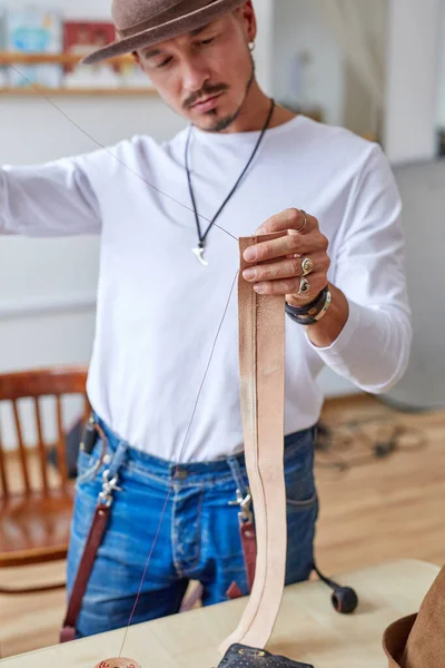 Designer masculin utilise des matériaux en tissu et différents outils pour coudre le chapeau — Photo
