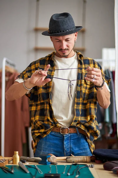 Giovane gioielliere caucasico artigiano sta per indossare catena fatta a mano sul collo — Foto Stock