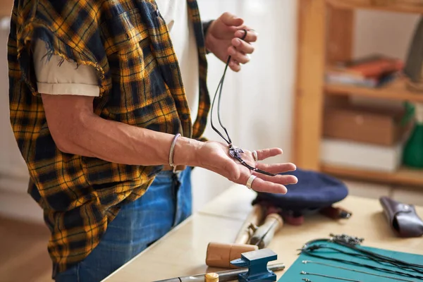 Local de trabalho de um joalheiro, homem segurando correntes feitas à mão em mãos — Fotografia de Stock