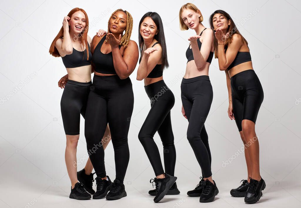 group of young diverse women in black sportive wear blowing kiss on camera