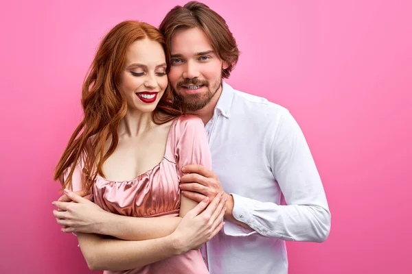 Beautiful caucasian couple hugging, posing in studio on pink background — Stock Photo, Image