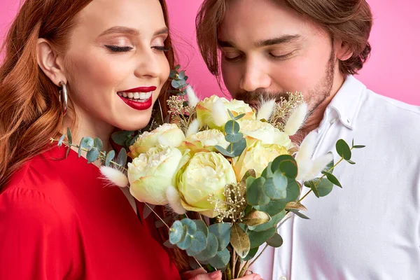 Ευτυχισμένο καυκάσιο ζευγάρι ερωτευμένο με ένα μπουκέτο λουλούδια στο στούντιο — Φωτογραφία Αρχείου