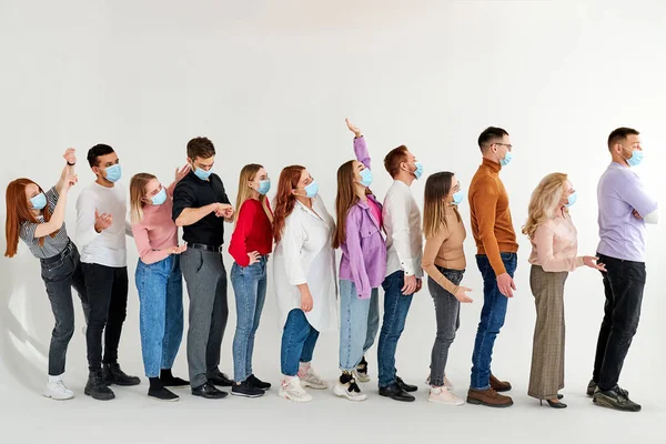 Jóvenes caucásicos esperando en fila practicando distanciamiento social en la tienda de la ciudad, en cola — Foto de Stock