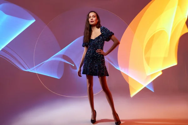 Fashionable stylish model on multi-colored freeze light vortexes in the background — Stock Photo, Image