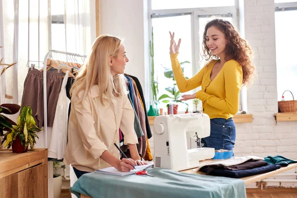 Diseñadores de moda caucásicos de la ropa de las mujeres jóvenes discutir el color y la forma, estilo de costura vestido —  Fotos de Stock