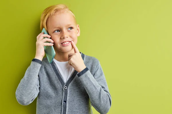 Přemýšlivý zasněný chlapec stojí v rozjímání, zatímco mluví po telefonu — Stock fotografie