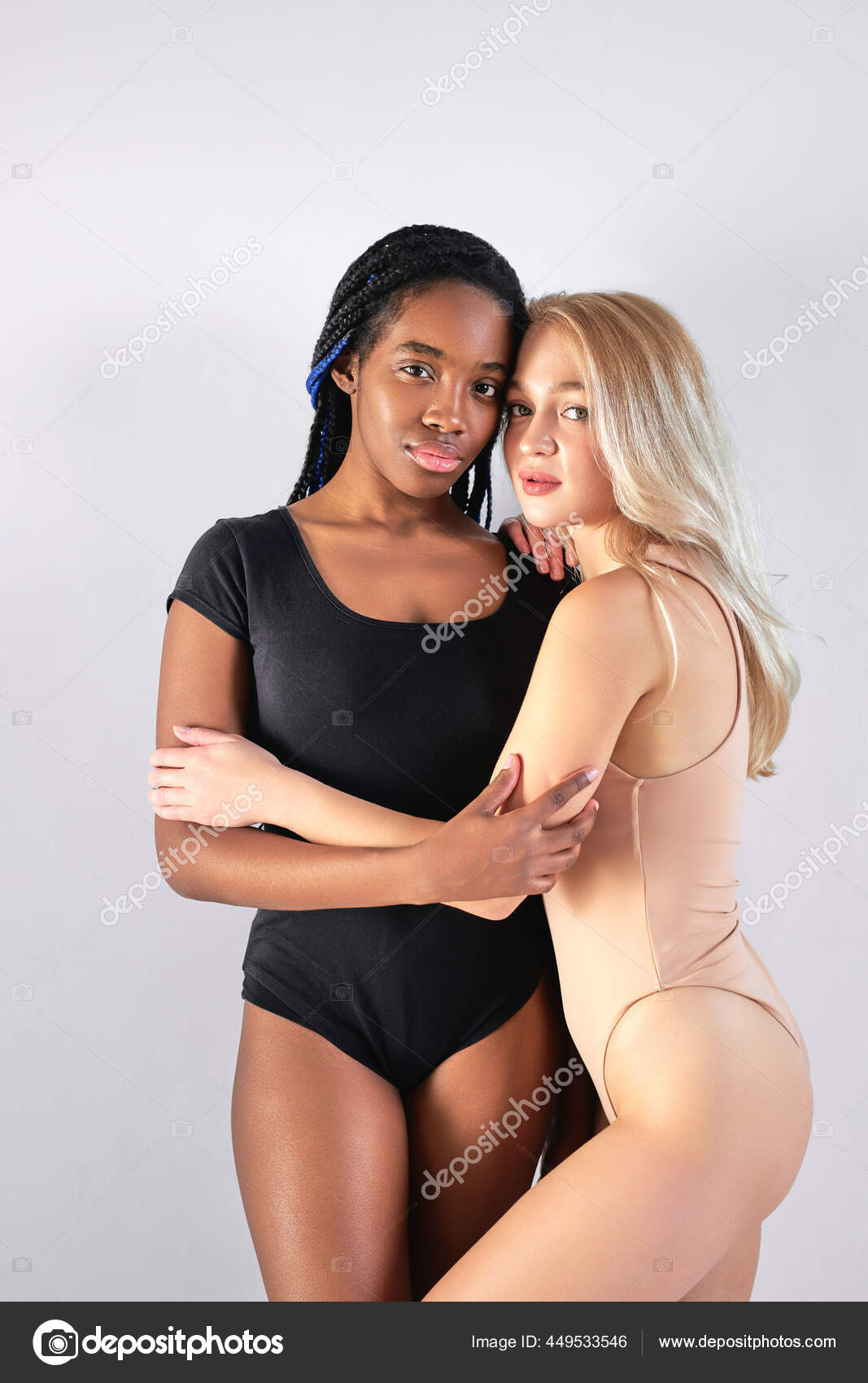 Attractive slim two diverse women in underwear posing hugging each