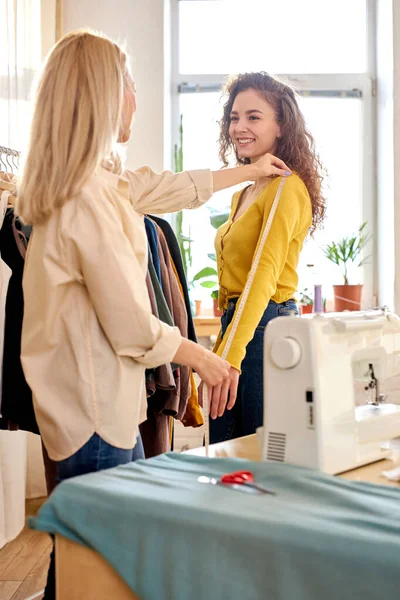 Diseñador de costurera moderna que mide una ropa para la mujer modelo de sastrería en el taller —  Fotos de Stock