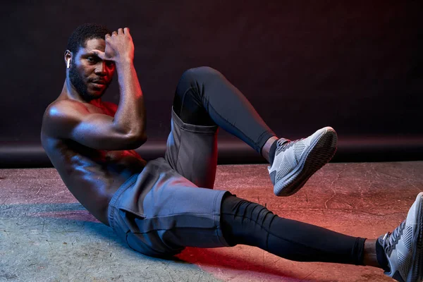 Póló nélküli afrikai fitt férfi gyakorolja a földön — Stock Fotó