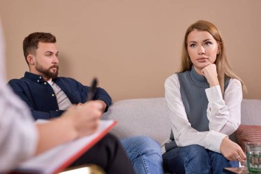 Evlilik danışmanıyla görüşürken üzgün genç bir eş ve kocası.