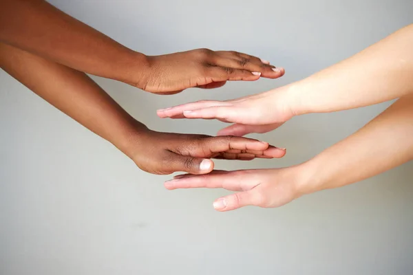 diverse female hands on top of each other, women keeping empty palm on gray isolated background