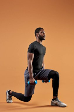 Sportif giyinen yakışıklı siyah afro erkek ağırlıkla egzersiz yapar, dambıl kullanır.