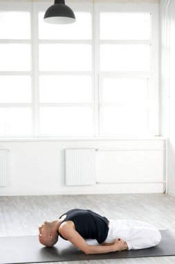 Kafkas yogası yapan deneyimli kel bir adam içeride yoga pozları veriyor.