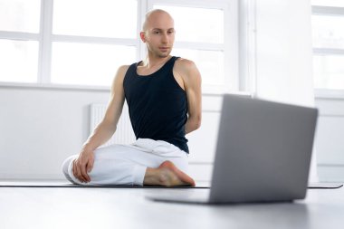 Cihazlarla çevrimiçi eğitim. Yoga yapan Yogi erkek, gündüz antrenman videosu izliyor.