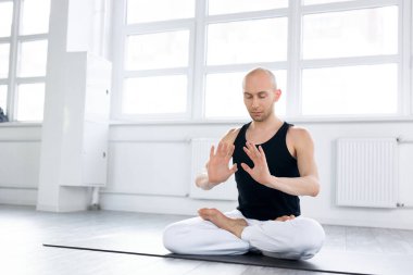 Profesyonel yogacı yerde oturup yoga eğitimi alır.