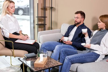 Hasta ailesi hakkında bilgi alan aile psikologu terapi seansı sırasında not alan danışman.