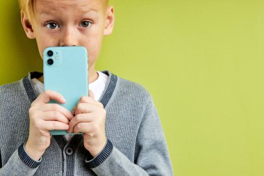 Akıllı telefonlu şaşkın çocuk bir şey saklıyor, cep telefonunda bir sır.