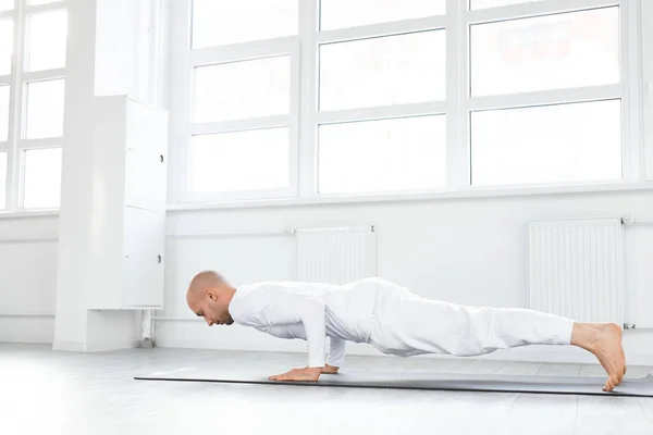 Вид сбоку на человека, держащего равновесие на руках, делающего упражнения йоги — стоковое фото