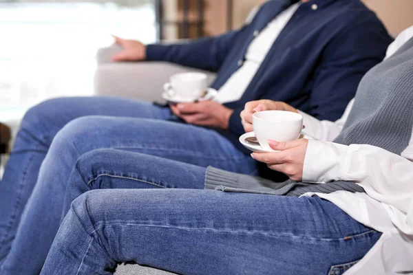 side view on cropped couple holding cups of coffee at psychologist therapy session