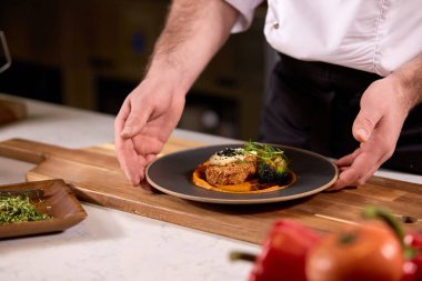 Profesyonel aşçı tarafından temsil edilen siyah tabakta lezzetli yemekler.