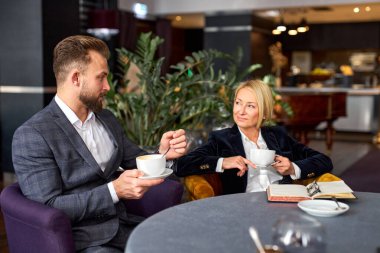 İki iş ortağı bir fincan kahve içerken sohbet ediyorlar.