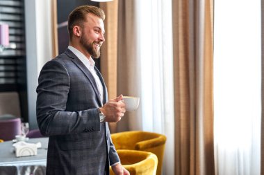 Otelde bir fincan kahvesi olan yakışıklı sakallı bir iş adamı.