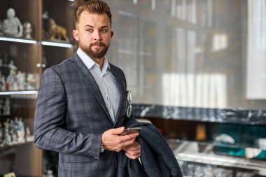 Ciddi düşünceli bir iş adamı cep telefonu standında tefekkür ediyor.