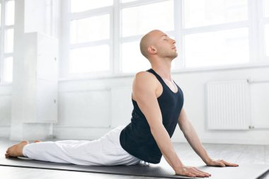 Kaslı beyaz adam vücut çalışıyor, esnek omurga egzersizleri yapıyor, urdhva mukha shvanasana, yukarı bakan köpek pozu