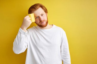 Tatmin olmamış kızıl saçlı erkek öğrencinin uykuya ihtiyacı var, bir fincan kahvenin yanında dur.