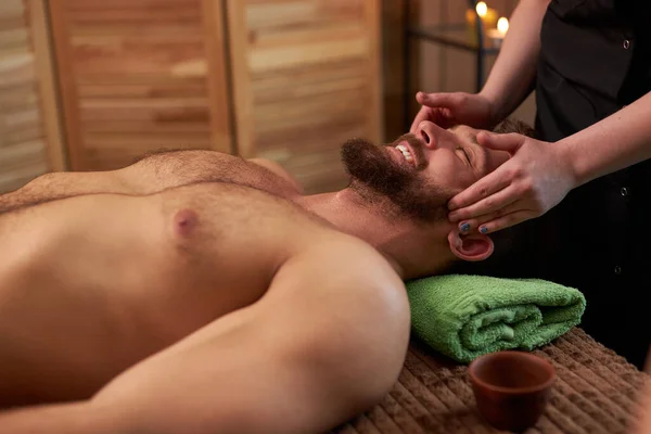 Massage therapist gives head massage to man